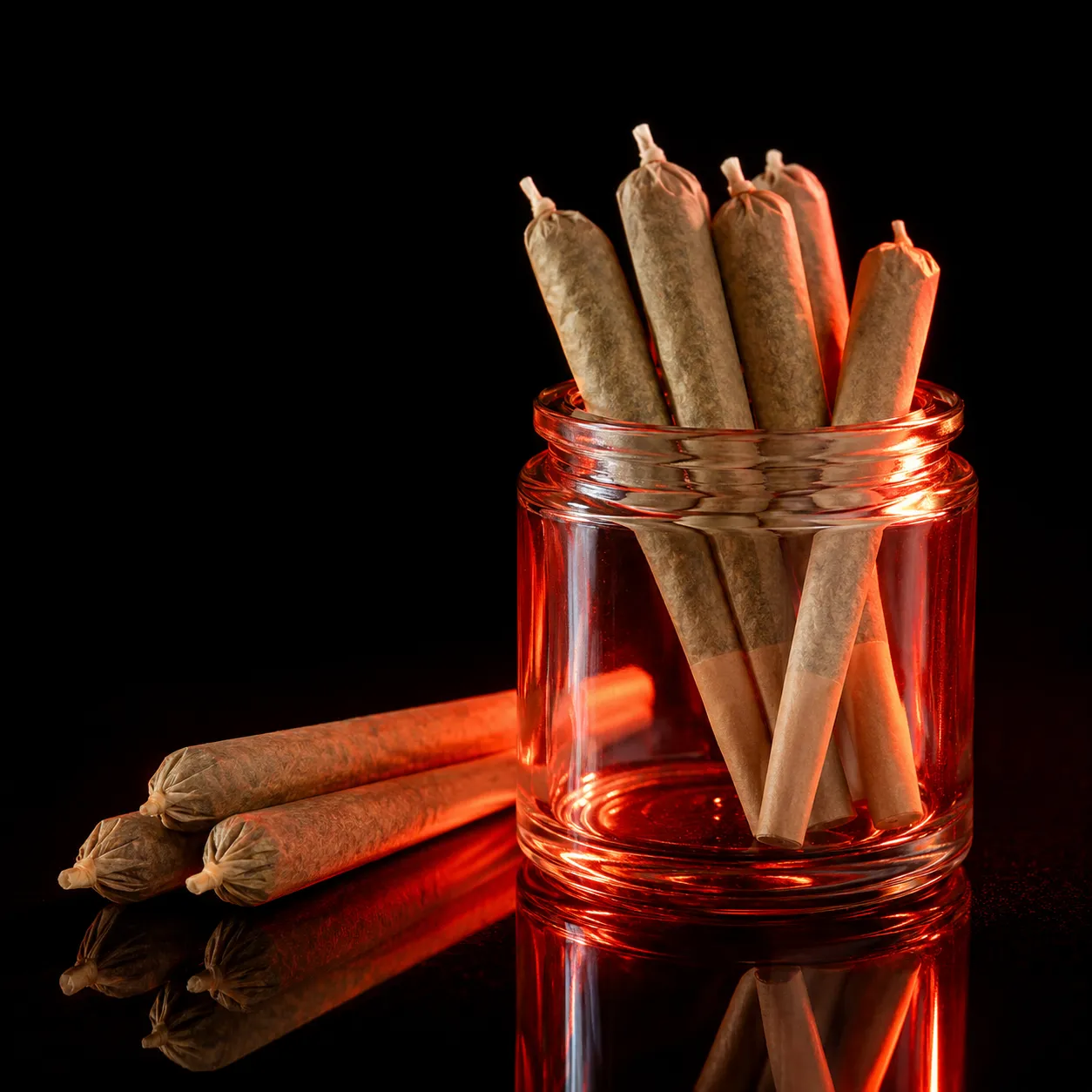 A hand holding a lit cannabis pre-roll