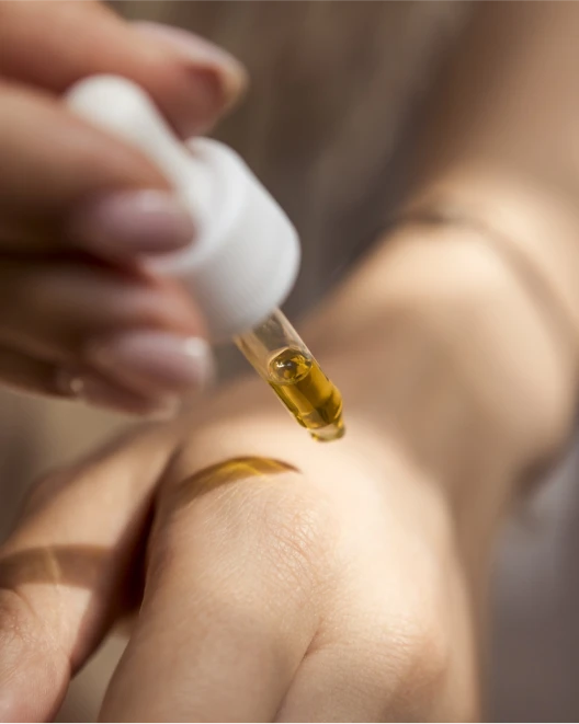 Close up of a person using a CBD oil dropper on their hand